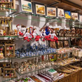 Narodnyi Dim Ukraina in Kyiv - glass shelves packed with diverse souvenir goods including wooden cottages, ceramic figurines and dolls in traditional costumes