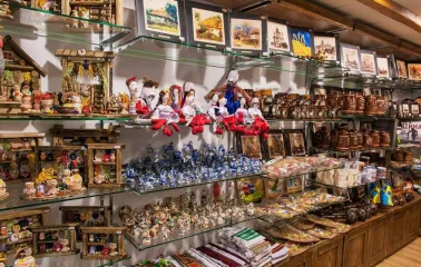Narodnyi Dim Ukraina in Kyiv - glass shelves packed with diverse souvenir goods including wooden cottages, ceramic figurines and dolls in traditional costumes