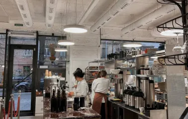 Spelta - baker working in the open kitchen preparing dough near the oven