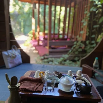 Chaguan in Kyiv - tea set with glass pitcher and white cups on wooden tray outdoors