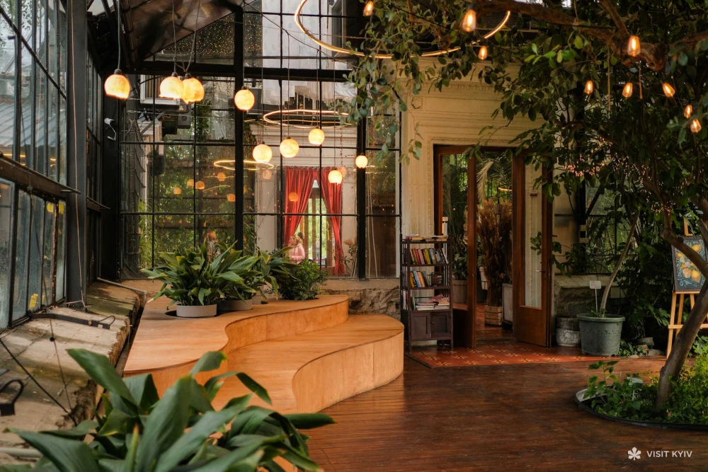 Cozy interior of the Greenhouse at VDNG in Kyiv with wooden seating and plants