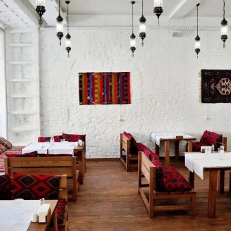 Musafir - cozy dining room with white brick walls and patterned cushions