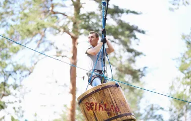 Seiklar Park in Kyiv - excited visitor gliding through the air inside a large wooden barrel suspended on cables