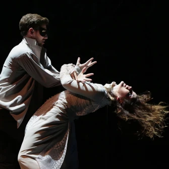 Teatr Lesi Ukrainky in Kyiv - dramatic scene featuring an actor in a mask holding a woman in a white dress