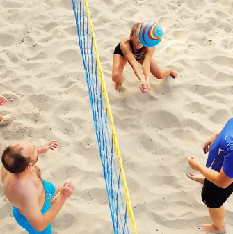 A group of people playing beach volleyball on a sand court