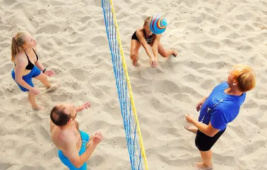 A group of people playing beach volleyball on a sand court