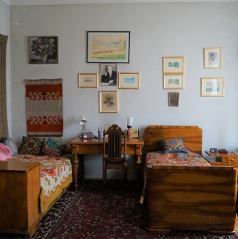 Muzei Tychyny in Kyiv - cozy historic bedroom featuring two wooden single beds with colorful covers, a writing desk, and walls adorned with framed artwork