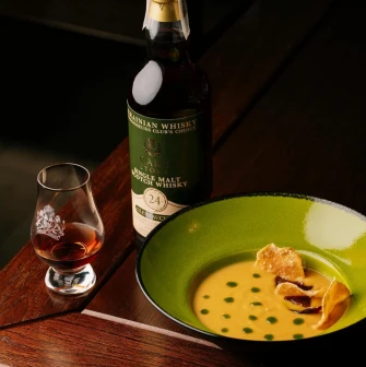 A dish and a glass of whisky on a wooden table at the "Whisky Corner" bar in Kyiv.