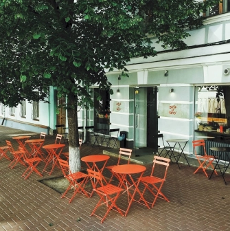 Svit Kavy in Kyiv - outdoor terrace with red folding tables and chairs under trees