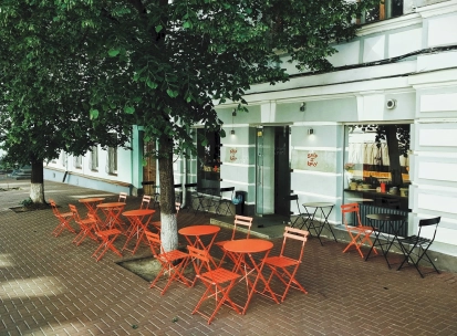 Svit Kavy in Kyiv - outdoor terrace with red folding tables and chairs under trees