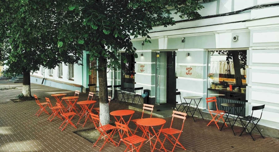 Svit Kavy in Kyiv - outdoor terrace with red folding tables and chairs under trees