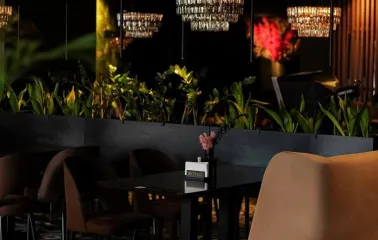 By Italy - dark interior, soft chairs and lots of greenery