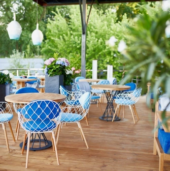 Restaurant Prychal - sunny wooden terrace with blue and white wire chairs