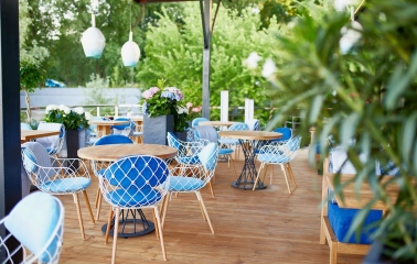 Restaurant Prychal - sunny wooden terrace with blue and white wire chairs
