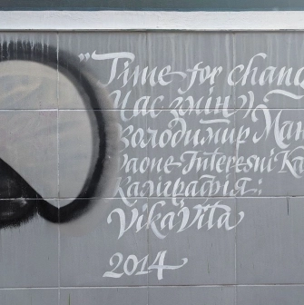 Time of Changes in Kyiv - tile on the wall with a white calligraphic caption of the mural