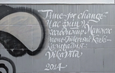 Time of Changes in Kyiv - tile on the wall with a white calligraphic caption of the mural