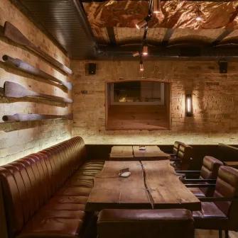 Pub Varvar bar - dimly lit interior featuring wooden tables and high booth seating along the wall