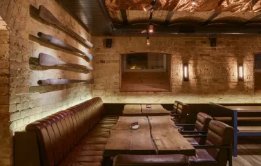 Pub Varvar bar - dimly lit interior featuring wooden tables and high booth seating along the wall