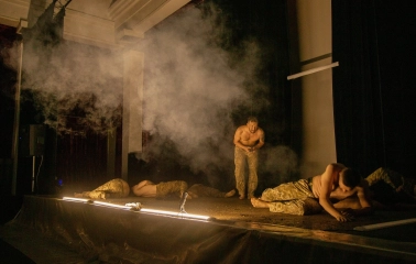 Teatr Voiennykh Dii in Kyiv - intense scene with actors crawling on the dark stage amidst smoke and light beams