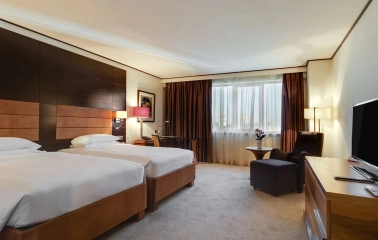 Room with two twin beds at the Hyatt Regency Kyiv with a work desk and an armchair by the window