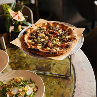 Restaurant Italiiska Redaktsiia - pizza on a stand and a salad on a wooden table