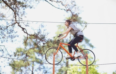 Seiklar Park in Kyiv - woman riding an orange bicycle suspended on a high wire