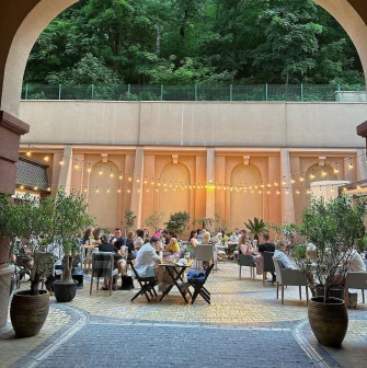 Restaurant Italiets iz Beiruta - view through an arch of the outdoor dining patio with strung lights
