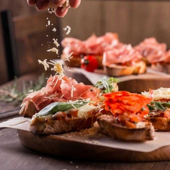 Photo of bruschetta being topped with grated cheese