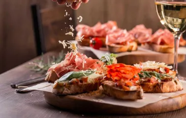 Photo of bruschetta being topped with grated cheese