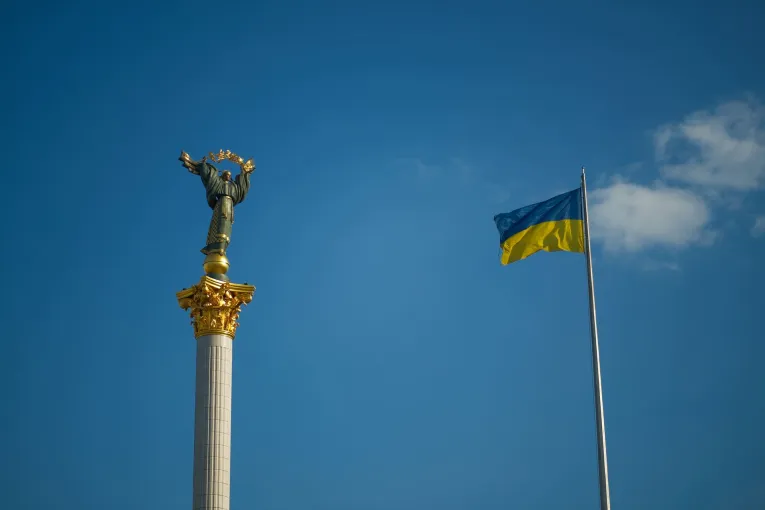 Monument to the Independence of Ukraine on Independence Square and the state flag against a blue sky in Kyiv