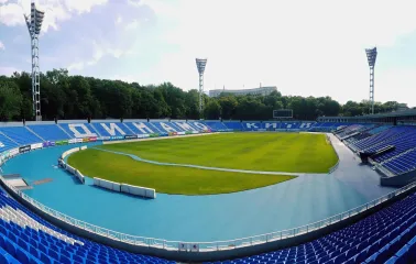 Dynamo Stadium in Kyiv - panoramic view from the stands showing the green pitch and blue seats with "Dynamo" and "Kyiv" lettering