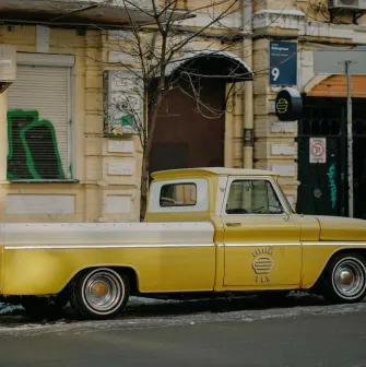 A yellow vintage pickup truck parked in front of OG Burger in Kyiv