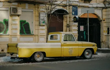 A yellow vintage pickup truck parked in front of OG Burger in Kyiv