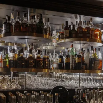 Bar shelves with bottles of alcoholic beverages and glasses