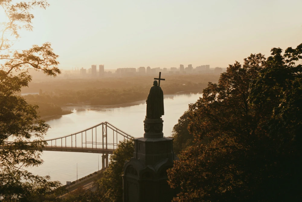 Monument to Volodymyr the Great - silhouette of the statue overlooking the Dnipro River and bridge in golden light