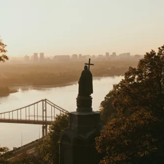 Monument to Vladimir the Great - silhouette of the statue overlooking the Dnipro River and bridge in golden light