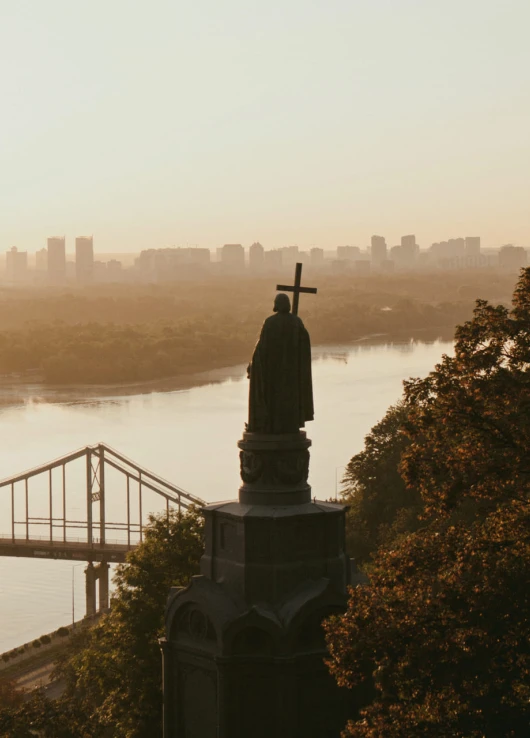 Monument to Volodymyr the Great - silhouette of the statue overlooking the Dnipro River and bridge in golden light