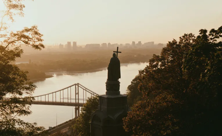 Monument to Vladimir the Great - silhouette of the statue overlooking the Dnipro River and bridge in golden light