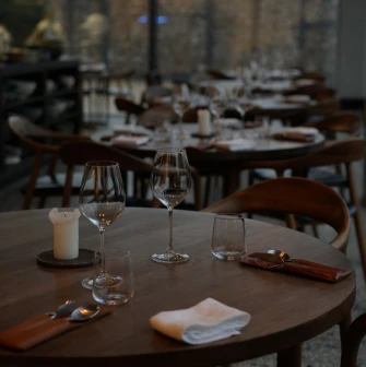 Empty round wooden table set for dinner with wine glasses and candles