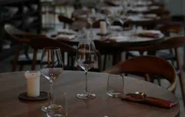 Empty round wooden table set for dinner with wine glasses and candles