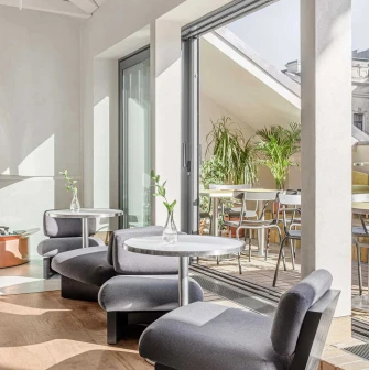 Interior lounge area with modern low chairs, offering a view of an outdoor terrace