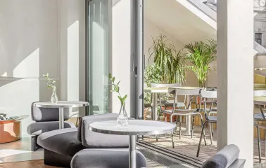 Interior lounge area with modern low chairs, offering a view of an outdoor terrace