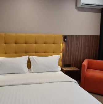 Double bed with yellow headboard in a Bontiak Hotel room