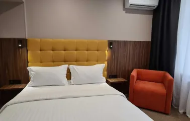 Double bed with yellow headboard in a Bontiak Hotel room