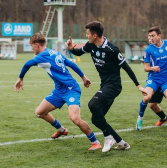 Футболісти в синій та чорній формі ведуть боротьбу за м'яч на полі Оболонь Арени