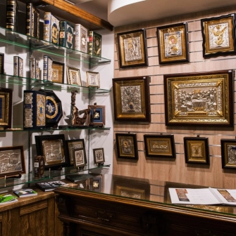 Narodnyi Dim Ukraina in Kyiv - display wall showcasing religious art with silver and gold framed icons and leather-bound books