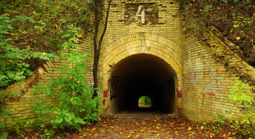 Lysa Hora in Kyiv - view through an old brick tunnel archway surrounded by autumn leaves