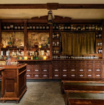 Pharmacy Museum in Kyiv - atmospheric interior of the apothecary featuring stone floors, dark wooden furniture filled with bottles, and candlelight creating a mysterious mood