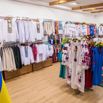 Narodnyi Dim Ukraina in Kyiv - bright spacious hall filled with racks of white and colorful embroidered shirts next to a Ukrainian flag