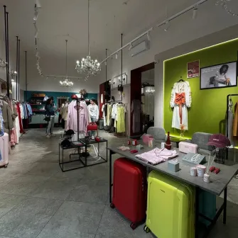 Kapsula in Kyiv - bright and spacious showroom interior with high ceilings and crystal chandeliers displaying racks of fashionable clothes and suitcases
